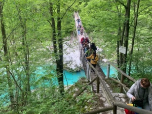 people crossing soča river bridge